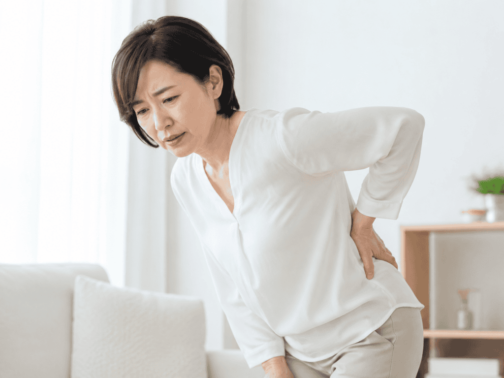 急な腰の痛みで腰に手を添える女性